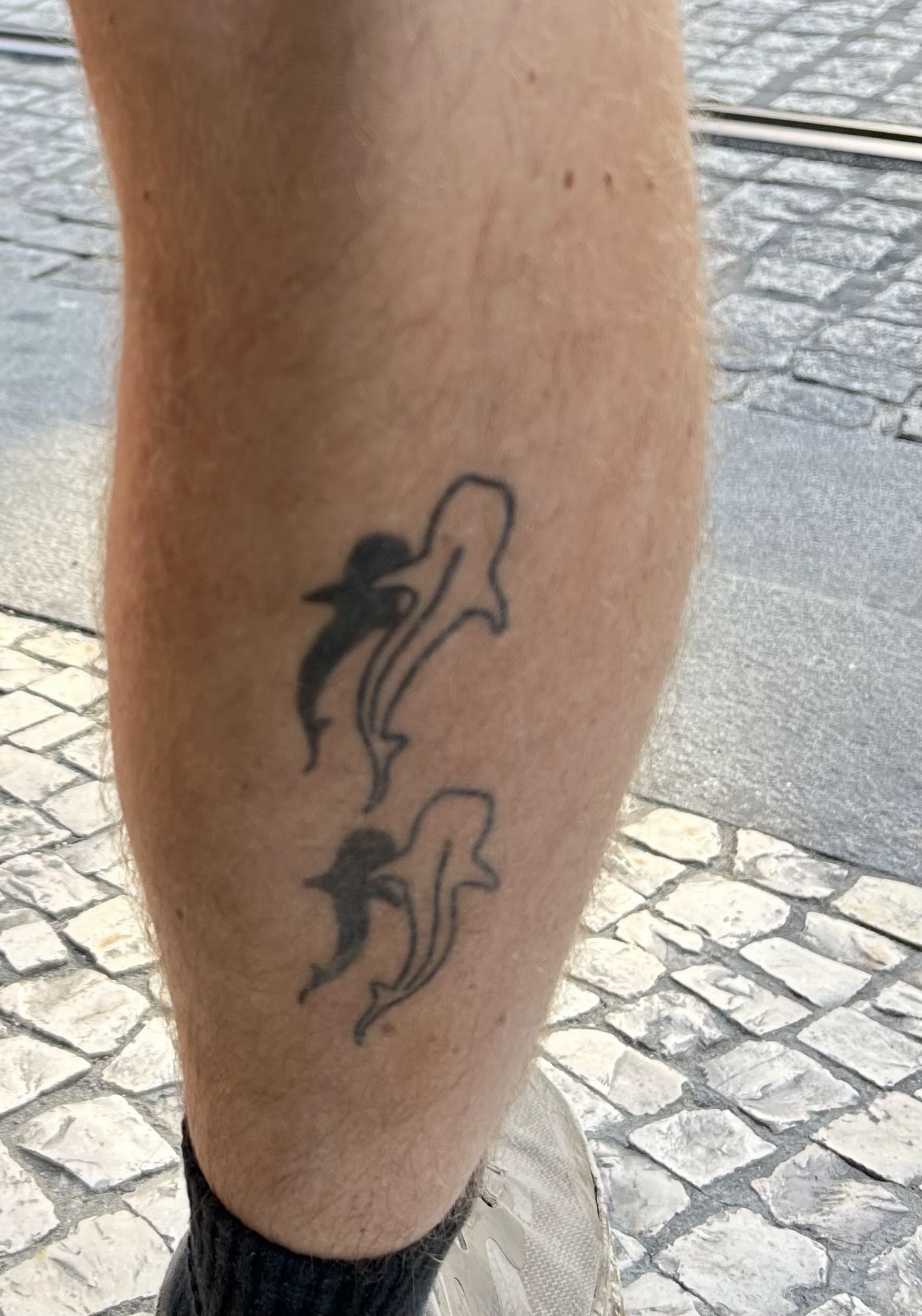 Un acercamiento a dos tatuajes de tiburón ballena en la parte posterior de la pantorrilla de Ian.